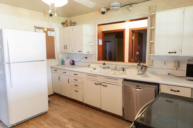 kitchen with light wood-type flooring, stainless steel dishwasher, sink, white refrigerator, and white cabinetry