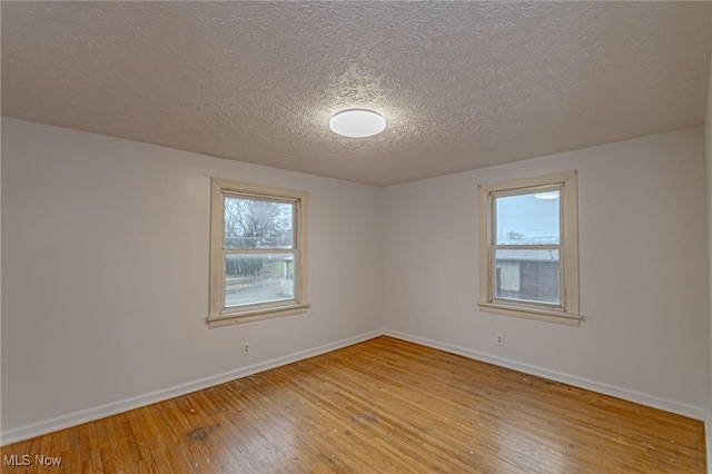 empty room with a textured ceiling and light wood-type flooring