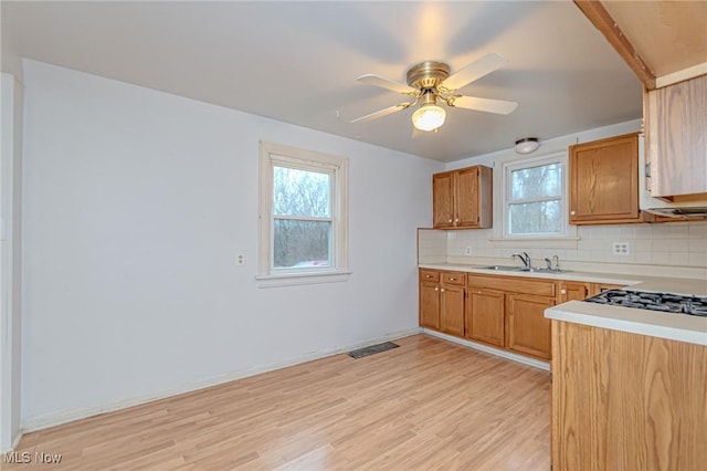 kitchen with backsplash, light hardwood / wood-style flooring, ceiling fan, and sink