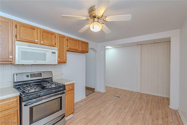 kitchen with decorative backsplash, stainless steel range with gas cooktop, ceiling fan, and light wood-type flooring