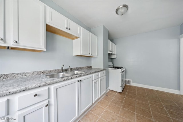 kitchen with white range with gas stovetop, light tile patterned flooring, white cabinetry, and sink