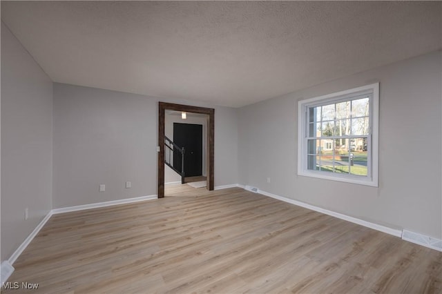 empty room featuring a textured ceiling and light hardwood / wood-style flooring