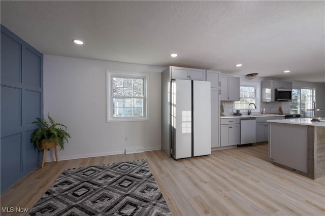 kitchen with sink, decorative backsplash, light wood-type flooring, a textured ceiling, and appliances with stainless steel finishes