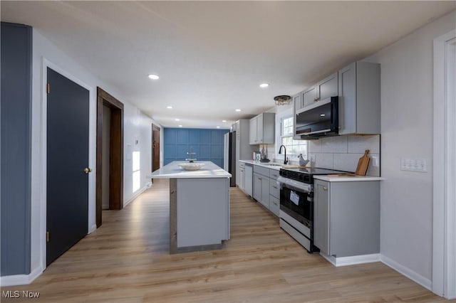 kitchen with gray cabinetry, white range with electric stovetop, a kitchen island, and sink