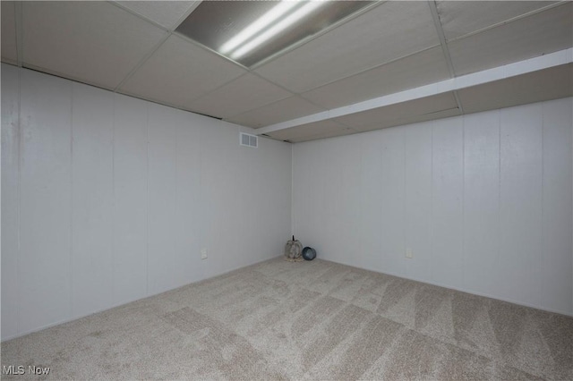 basement featuring a paneled ceiling and carpet flooring