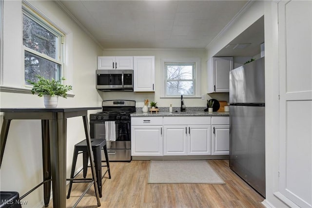 kitchen featuring sink, white cabinetry, stainless steel appliances, and light wood-type flooring