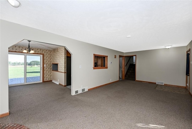 unfurnished living room with carpet floors and an inviting chandelier