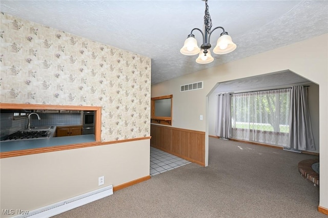 interior space featuring sink, decorative light fixtures, a baseboard radiator, a notable chandelier, and light colored carpet