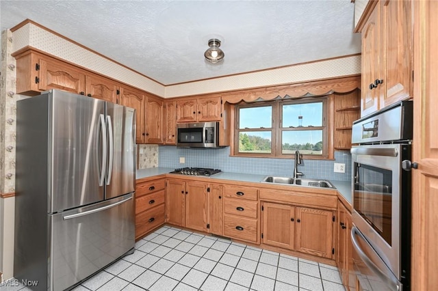 kitchen with sink, decorative backsplash, ornamental molding, a textured ceiling, and stainless steel appliances