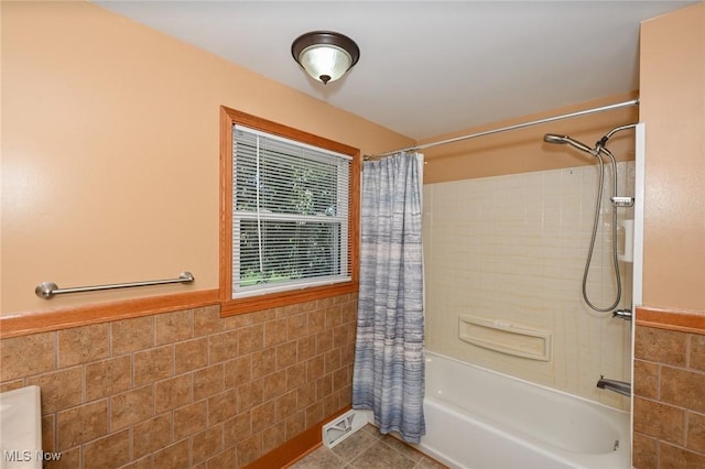 bathroom featuring tile patterned floors, shower / tub combo with curtain, and tile walls