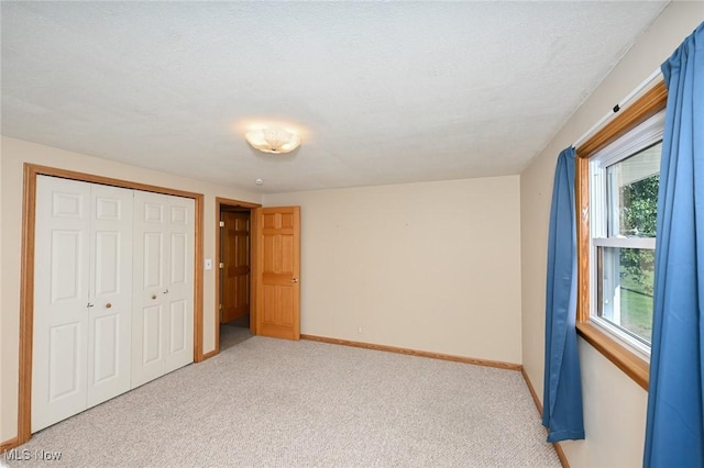 unfurnished bedroom with light colored carpet and a closet