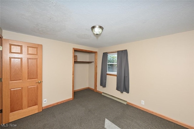 unfurnished bedroom featuring dark colored carpet, a textured ceiling, a closet, and a baseboard heating unit