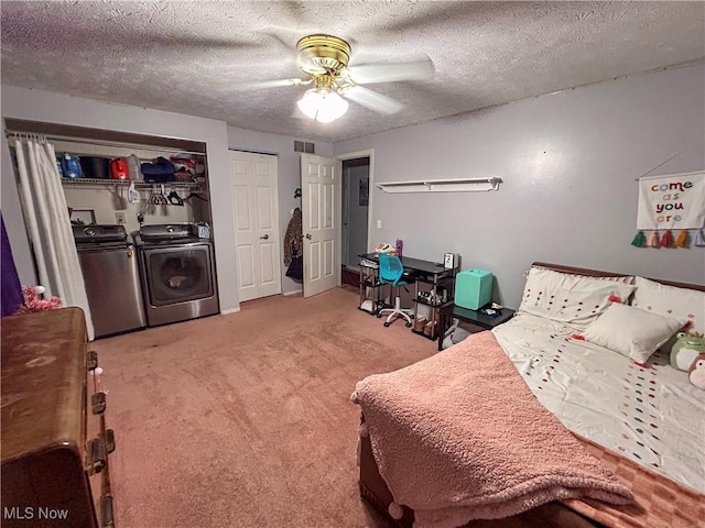 bedroom with light colored carpet, ceiling fan, washing machine and dryer, and a textured ceiling