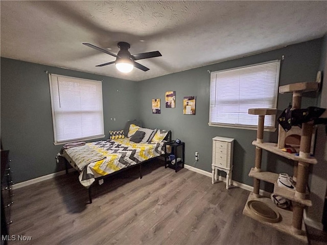 bedroom featuring ceiling fan, hardwood / wood-style floors, and a textured ceiling