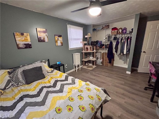 bedroom with dark wood-type flooring, ceiling fan, and a closet