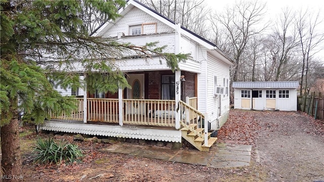 view of front of house featuring a porch and a storage shed