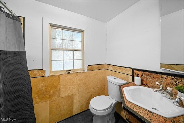 bathroom featuring toilet, tile walls, and sink