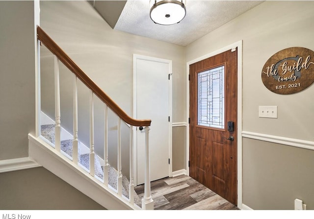 entryway with wood-type flooring and a textured ceiling