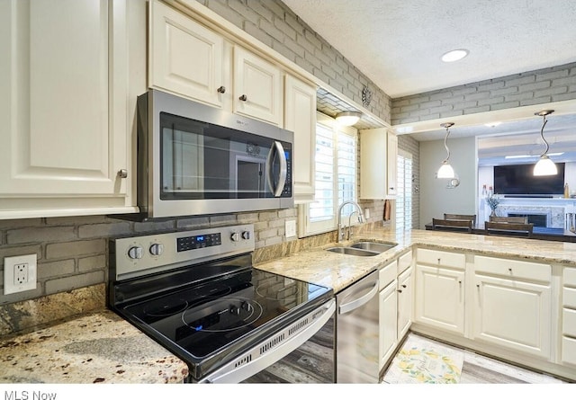 kitchen with pendant lighting, sink, decorative backsplash, a textured ceiling, and appliances with stainless steel finishes