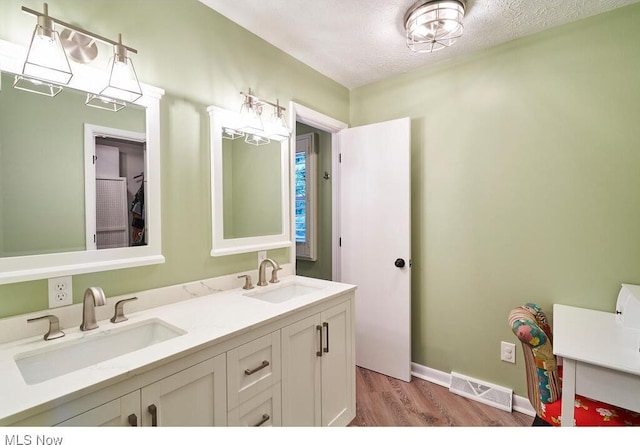 bathroom with hardwood / wood-style floors, vanity, and a textured ceiling