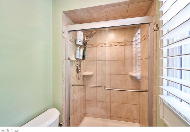 bathroom featuring toilet and a shower with shower door