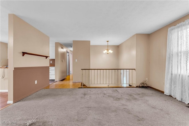 spare room with light carpet and an inviting chandelier