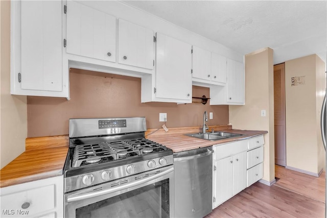 kitchen with white cabinetry, sink, light hardwood / wood-style floors, and appliances with stainless steel finishes