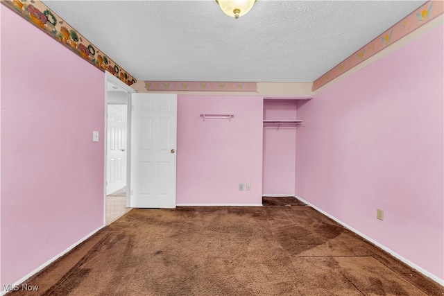 unfurnished bedroom featuring dark carpet, a textured ceiling, and a closet