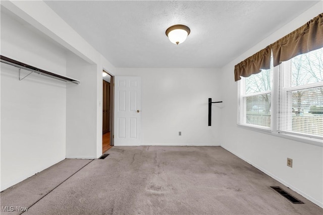 unfurnished bedroom with a textured ceiling, light carpet, and a closet