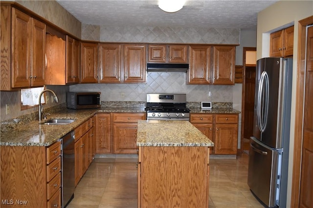 kitchen with a center island, light stone countertops, sink, and appliances with stainless steel finishes