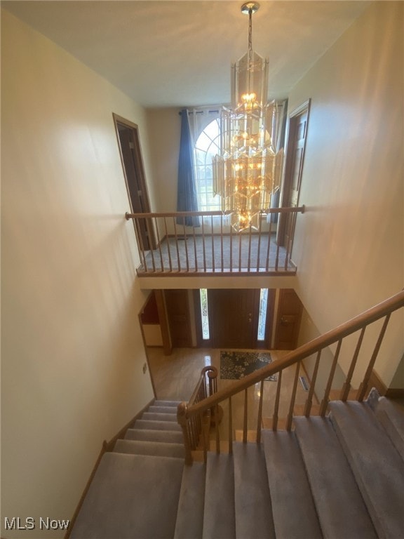 stairs with a chandelier and carpet floors