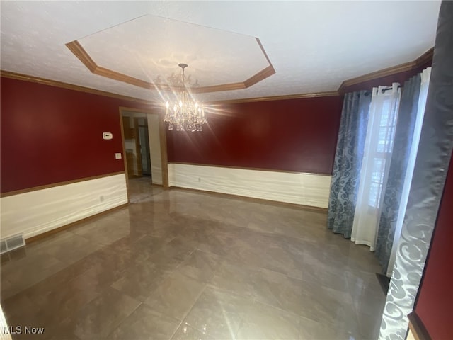 unfurnished room with a tray ceiling, ornamental molding, and a notable chandelier