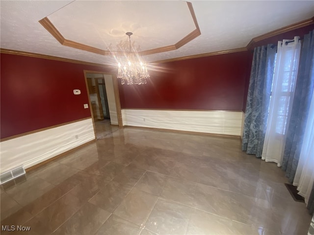 spare room featuring a textured ceiling, an inviting chandelier, and ornamental molding