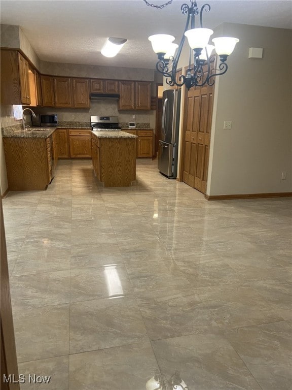 kitchen featuring pendant lighting, a center island, sink, appliances with stainless steel finishes, and a notable chandelier