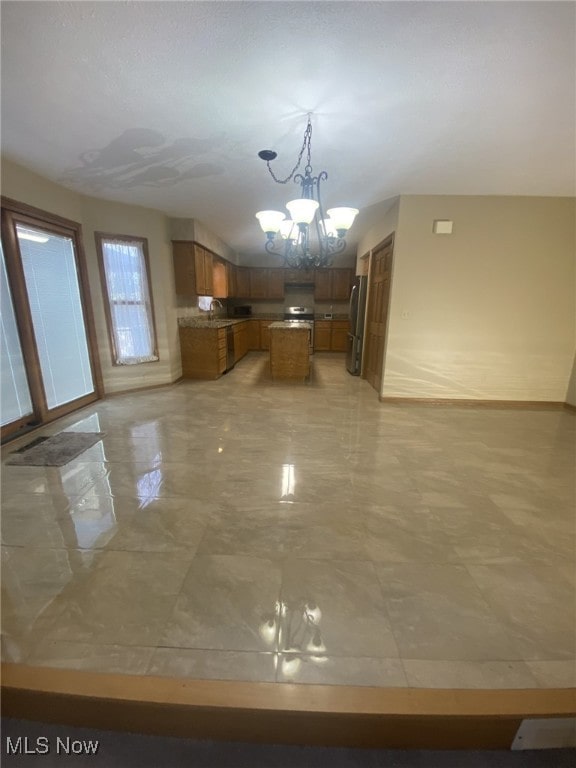 kitchen with extractor fan, pendant lighting, stainless steel appliances, and an inviting chandelier