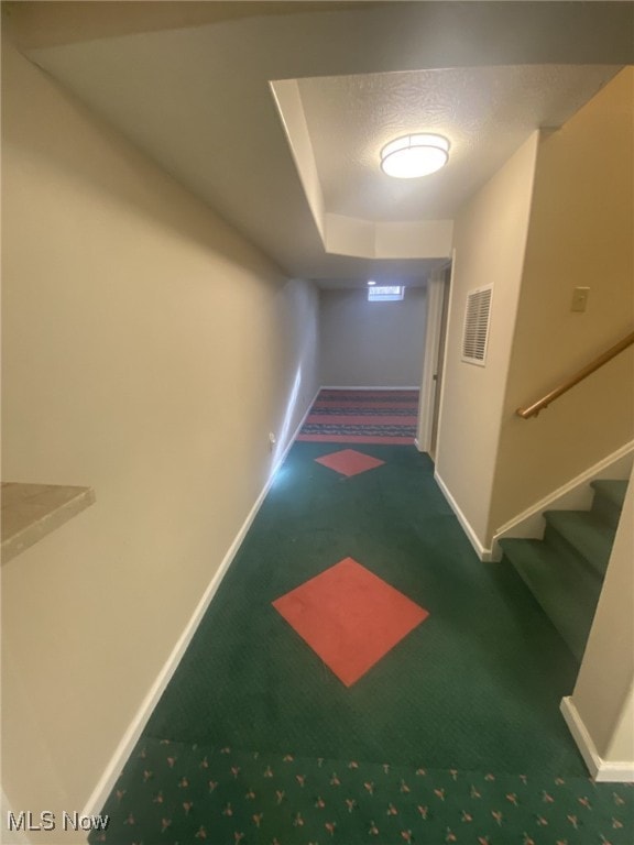 hallway featuring dark colored carpet and a textured ceiling