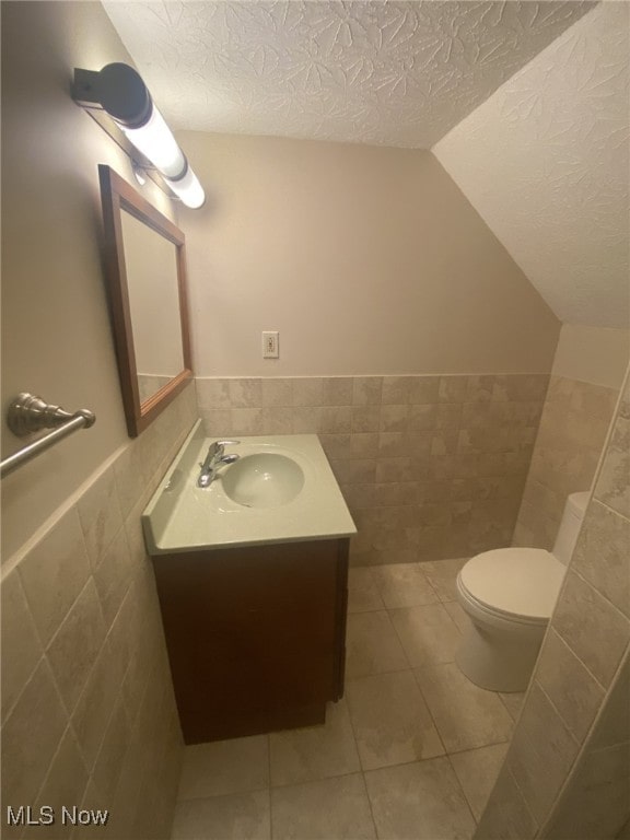 bathroom with tile patterned flooring, vanity, toilet, and tile walls