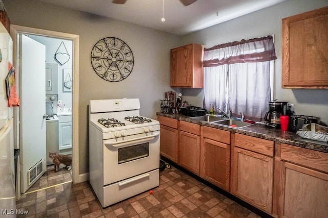 kitchen with ceiling fan, white gas range, and sink