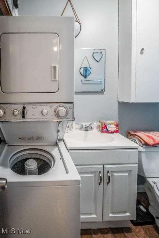 washroom with sink, cabinets, and stacked washer and clothes dryer