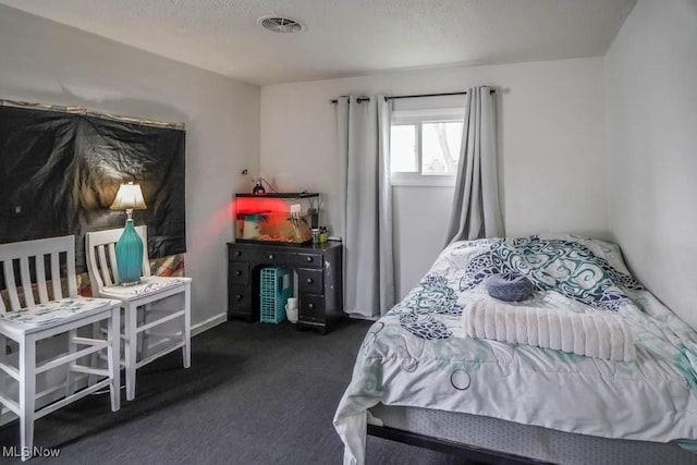 bedroom featuring dark colored carpet and a textured ceiling