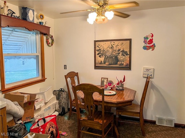 dining room featuring ceiling fan and dark carpet