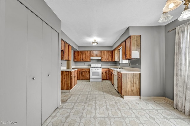 kitchen with sink, white appliances, and hanging light fixtures