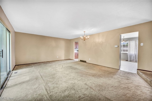 carpeted spare room with an inviting chandelier