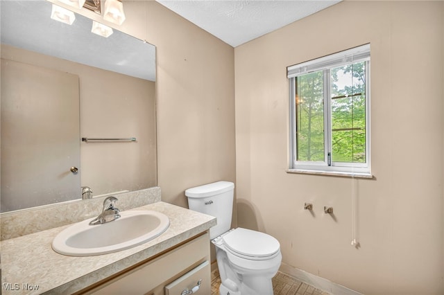 bathroom with a textured ceiling, vanity, and toilet