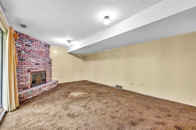 unfurnished living room featuring carpet, a textured ceiling, and a brick fireplace