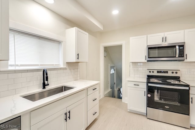 kitchen featuring light stone counters, sink, white cabinets, and appliances with stainless steel finishes