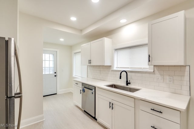 kitchen featuring sink, stainless steel appliances, light stone counters, decorative backsplash, and white cabinets