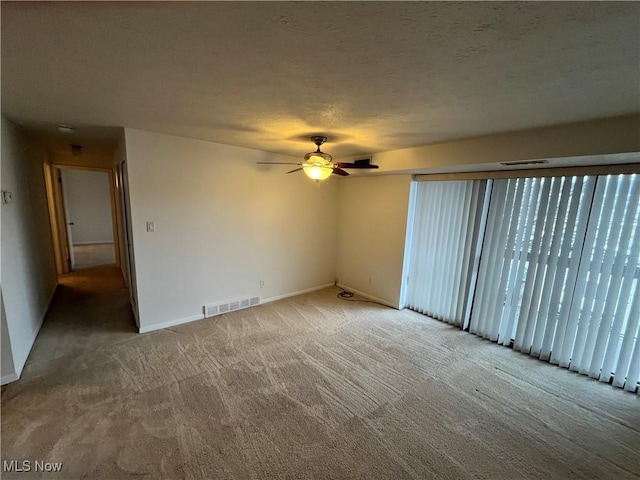 empty room featuring carpet flooring, ceiling fan, and a textured ceiling