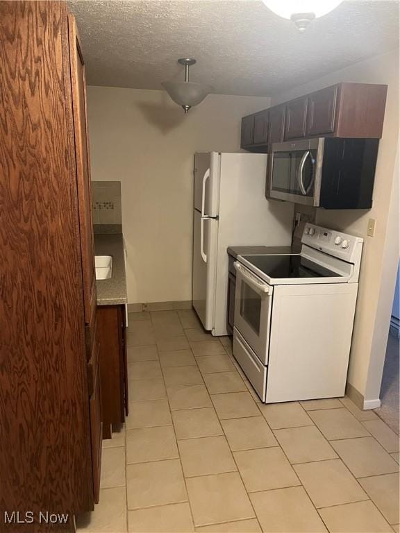 kitchen featuring white electric range oven, light tile patterned floors, and a textured ceiling