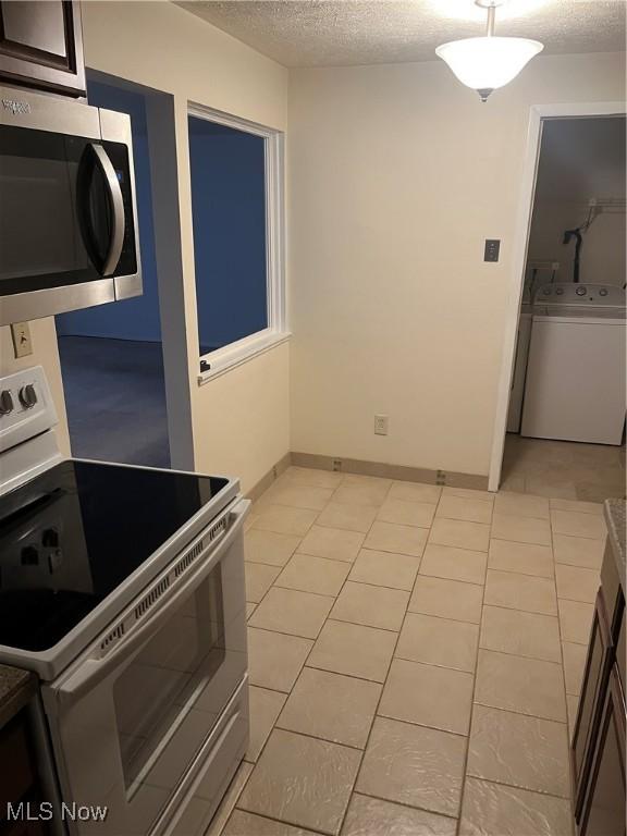 kitchen featuring washer / clothes dryer, a textured ceiling, dark brown cabinets, light tile patterned flooring, and white stove